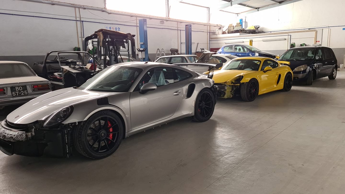 Interior da oficina Victor Ferreira Garage em Mundão, Viseu, com vários carros em pintura